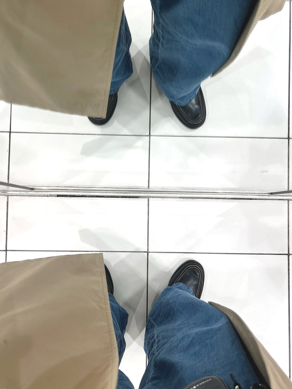 ブラック系のローファー、ブルー系のデニムパンツ、ブラック系のトートバッグを着用したメンズの春コーディネートの5枚目の写真