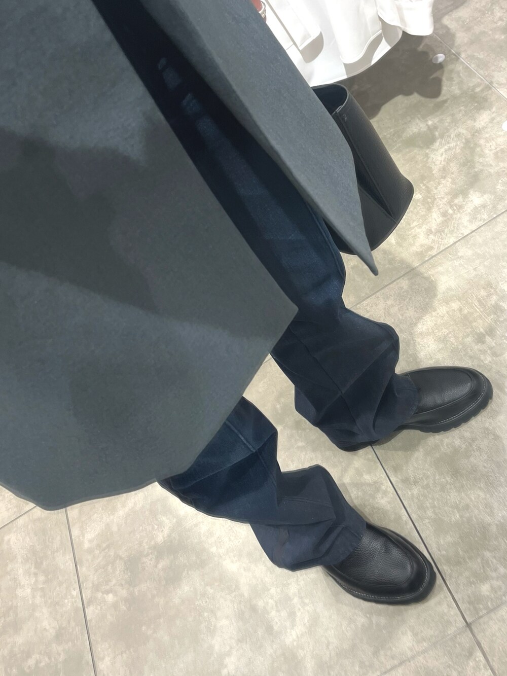 ブラック系のショルダーバッグ、ブラック系のドレスシューズ、ブルー系のデニムパンツを着用したメンズの春コーディネートの3枚目の写真