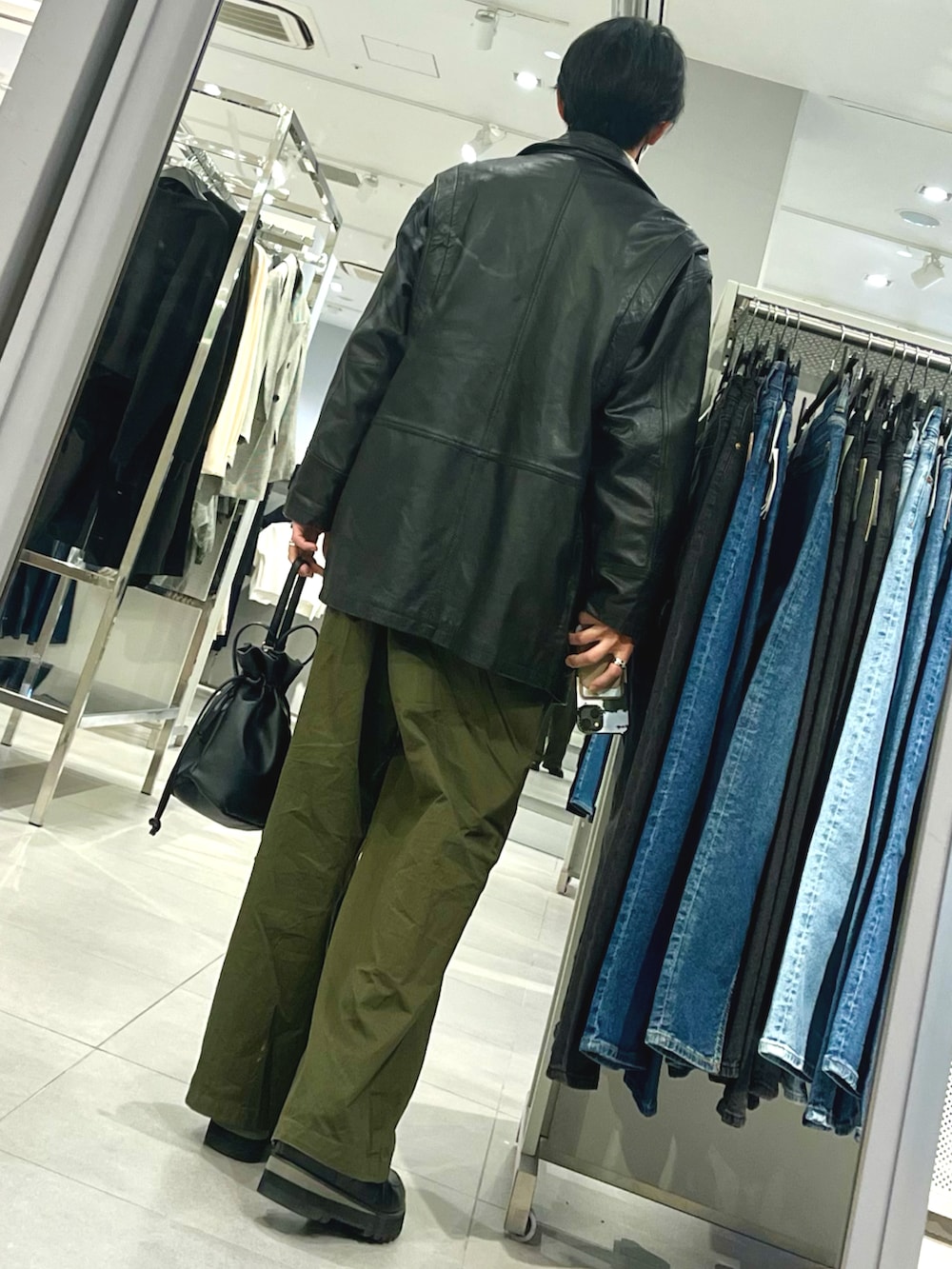 グリーン系のパンツ、ブラック系のドレスシューズ、ブラック系のジャケット/アウターを着用したメンズの冬コーディネートの2枚目の写真