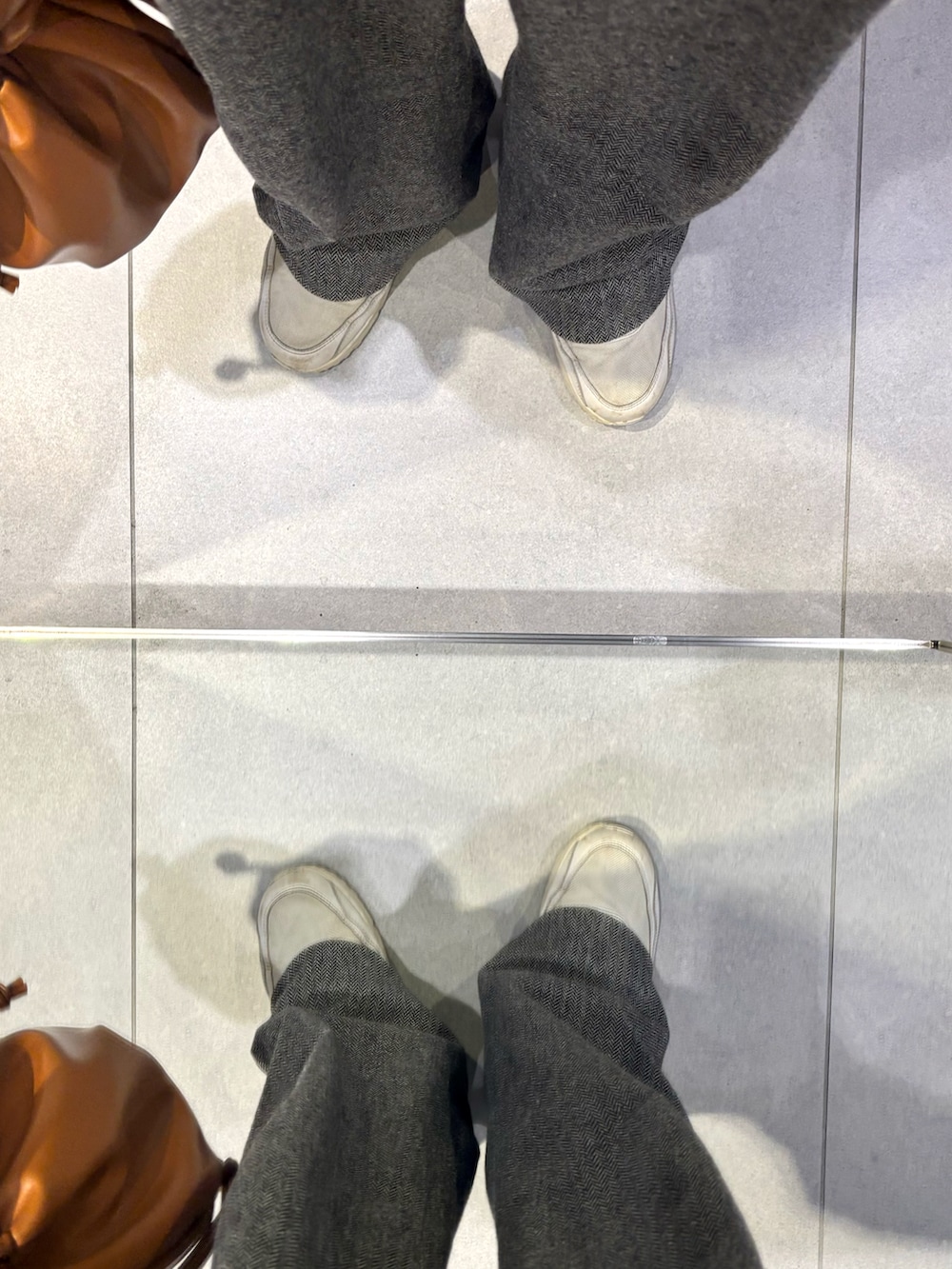 ブラウン系のショルダーバッグ、ホワイト系のスニーカー、ホワイト系のカーディガン/ボレロを着用したメンズの冬コーディネートの5枚目の写真