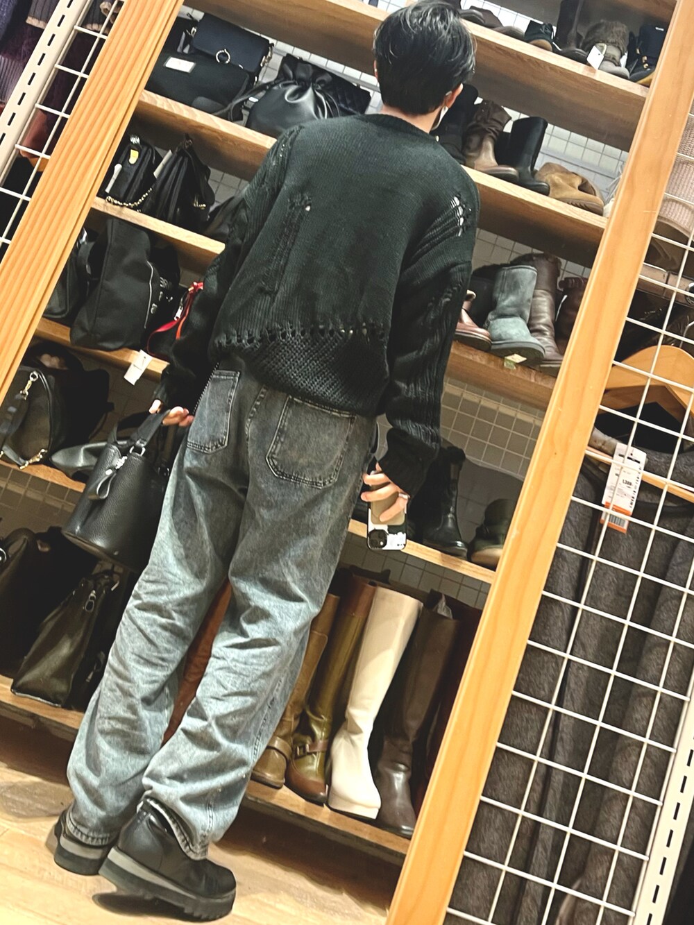 グレー系のデニムパンツ、ブラック系のニット/セーター、ブラック系のドレスシューズを着用したメンズの冬コーディネートの2枚目の写真
