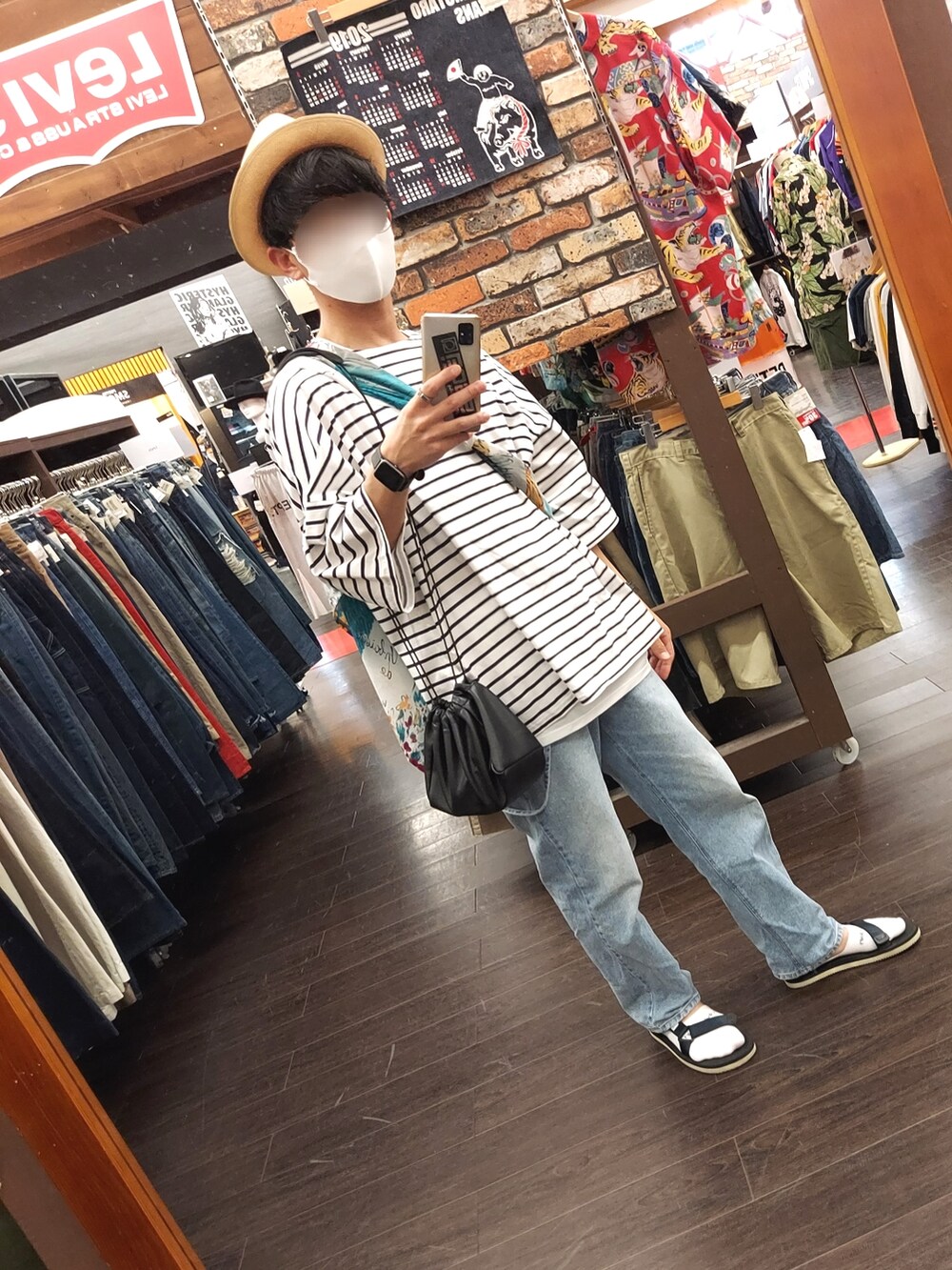ブルー系のデニムパンツ、ホワイト系のTシャツ/カットソー、ブラック系のサンダルを着用したメンズの夏コーディネートの5枚目の写真