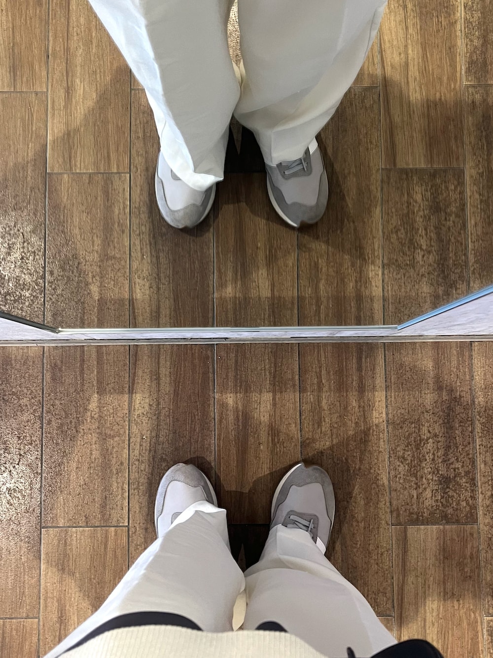 グレー系のスニーカー、ベージュ系のベスト、グレー系のショルダーバッグを着用したメンズの秋コーディネートの5枚目の写真