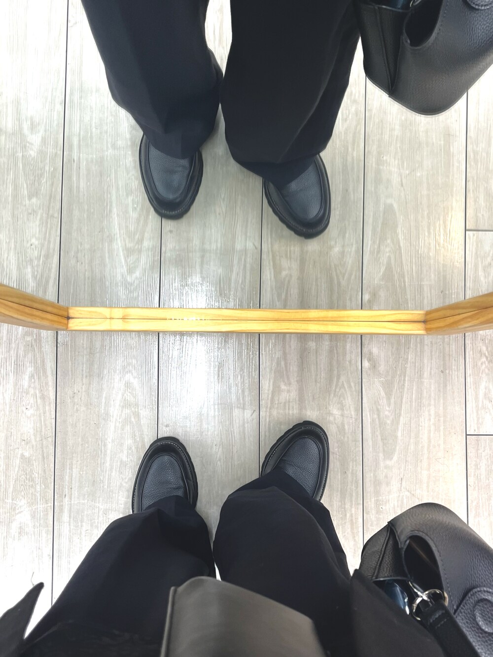 ブラック系のスラックス、ブラック系のドレスシューズ、ブラック系のショルダーバッグを着用したメンズの春コーディネートの5枚目の写真