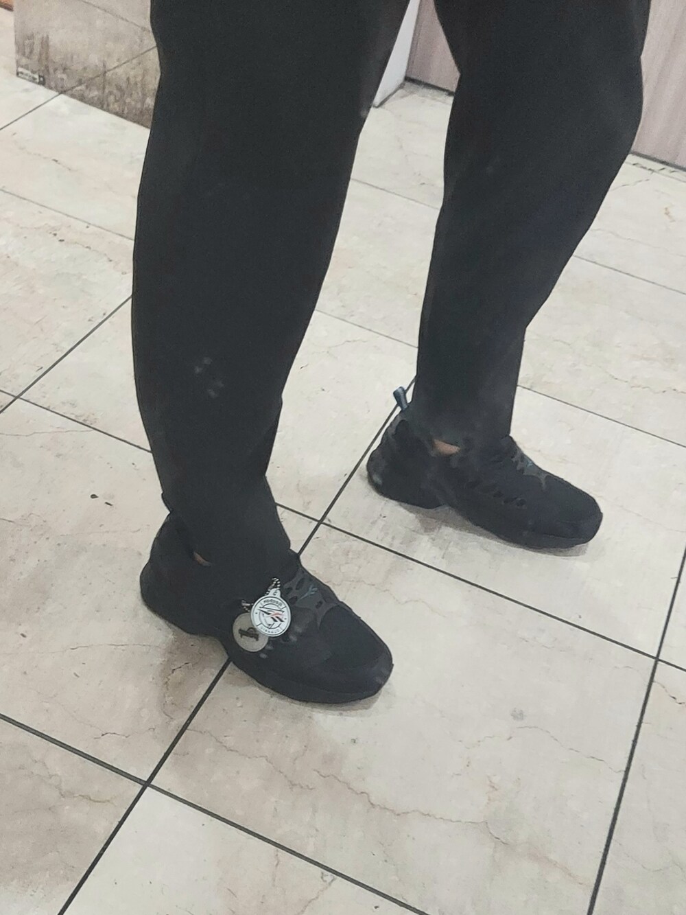 ブラック系のスニーカー、ブラック系のスラックス、ブラック系のショルダーバッグを着用したメンズの春コーディネートの4枚目の写真