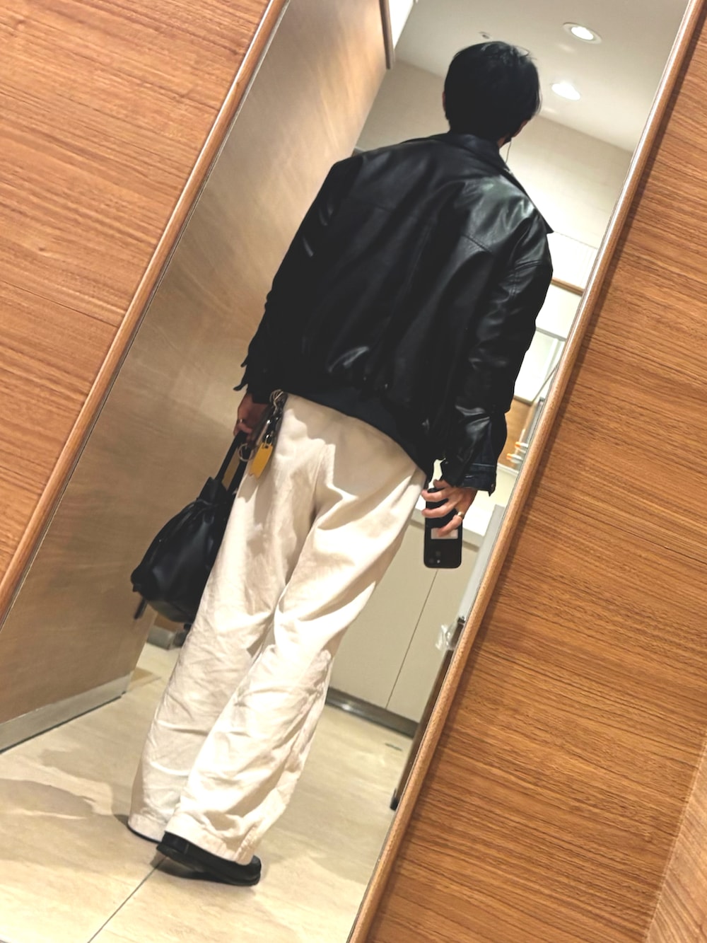 ブラック系のブルゾン、ホワイト系のパンツ、ブラック系のローファーを着用したメンズの春コーディネートの2枚目の写真