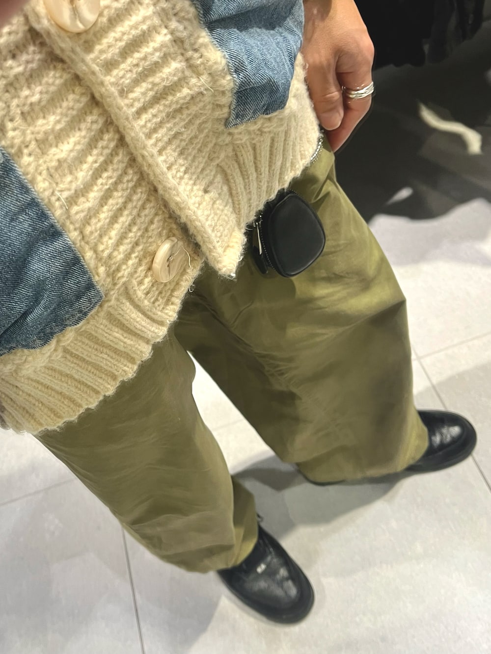 グリーン系のパンツ、ブラック系のスニーカー、ベージュ系のカーディガン/ボレロを着用したメンズの冬コーディネートの3枚目の写真