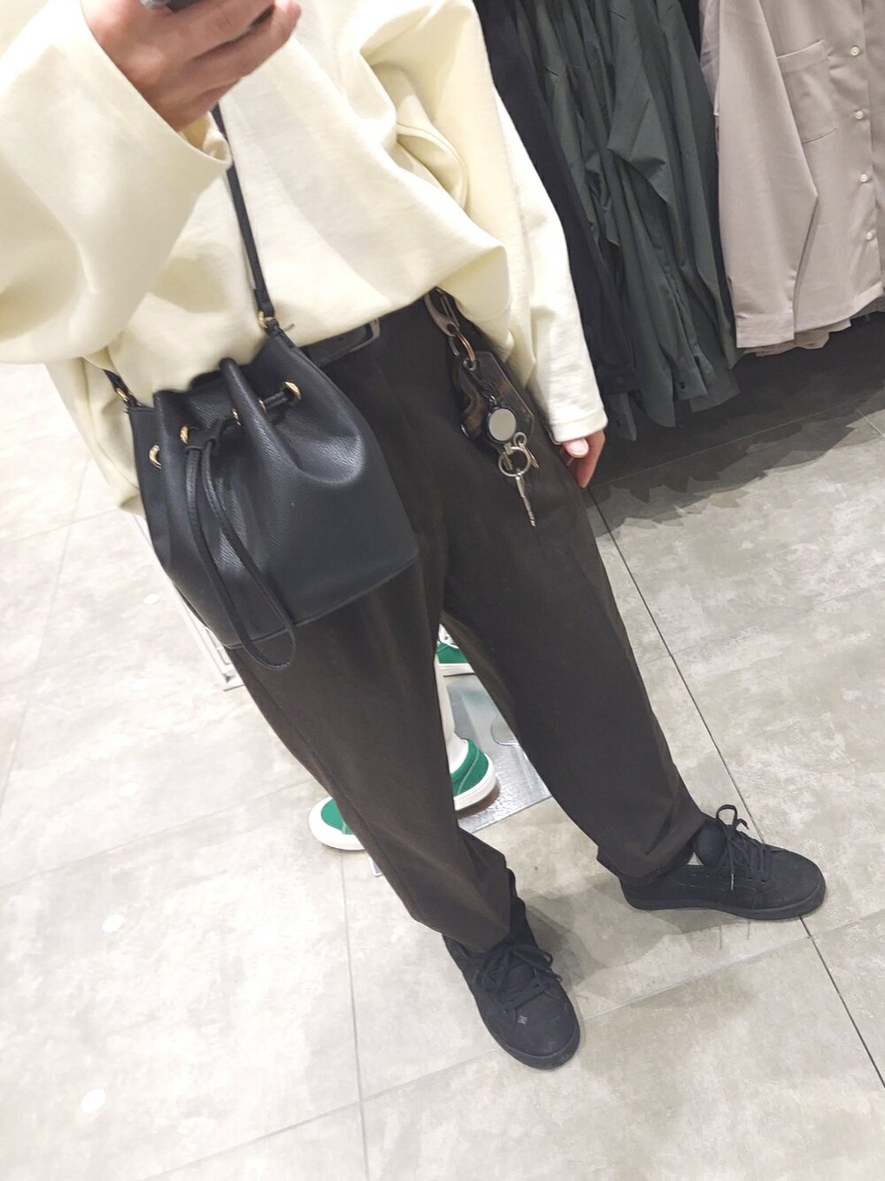 ブラウン系のパンツ、ブラック系のスニーカー、ホワイト系のニット/セーターを着用したメンズの春コーディネートの3枚目の写真