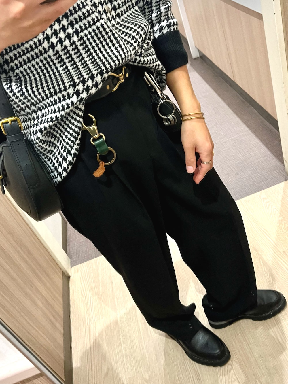 ブラック系のドレスシューズ、ブラック系のスラックス、ホワイト系のニット/セーターを着用したメンズの冬コーディネートの3枚目の写真