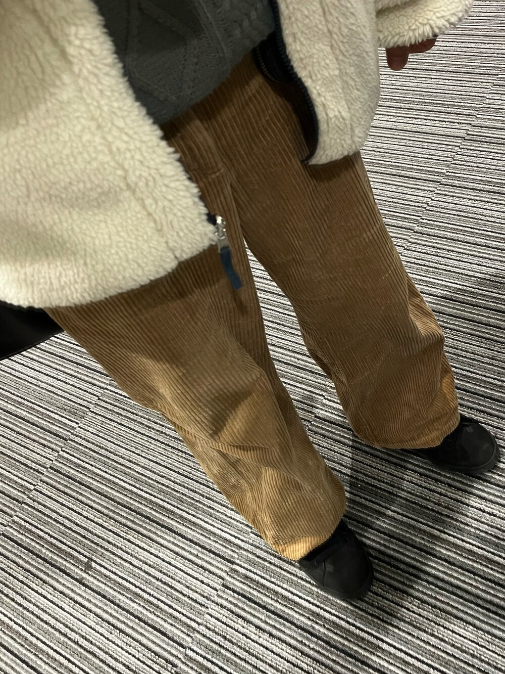 ブラウン系のパンツ、ブラック系のスニーカー、ブラック系のショルダーバッグを着用したメンズの春コーディネートの3枚目の写真