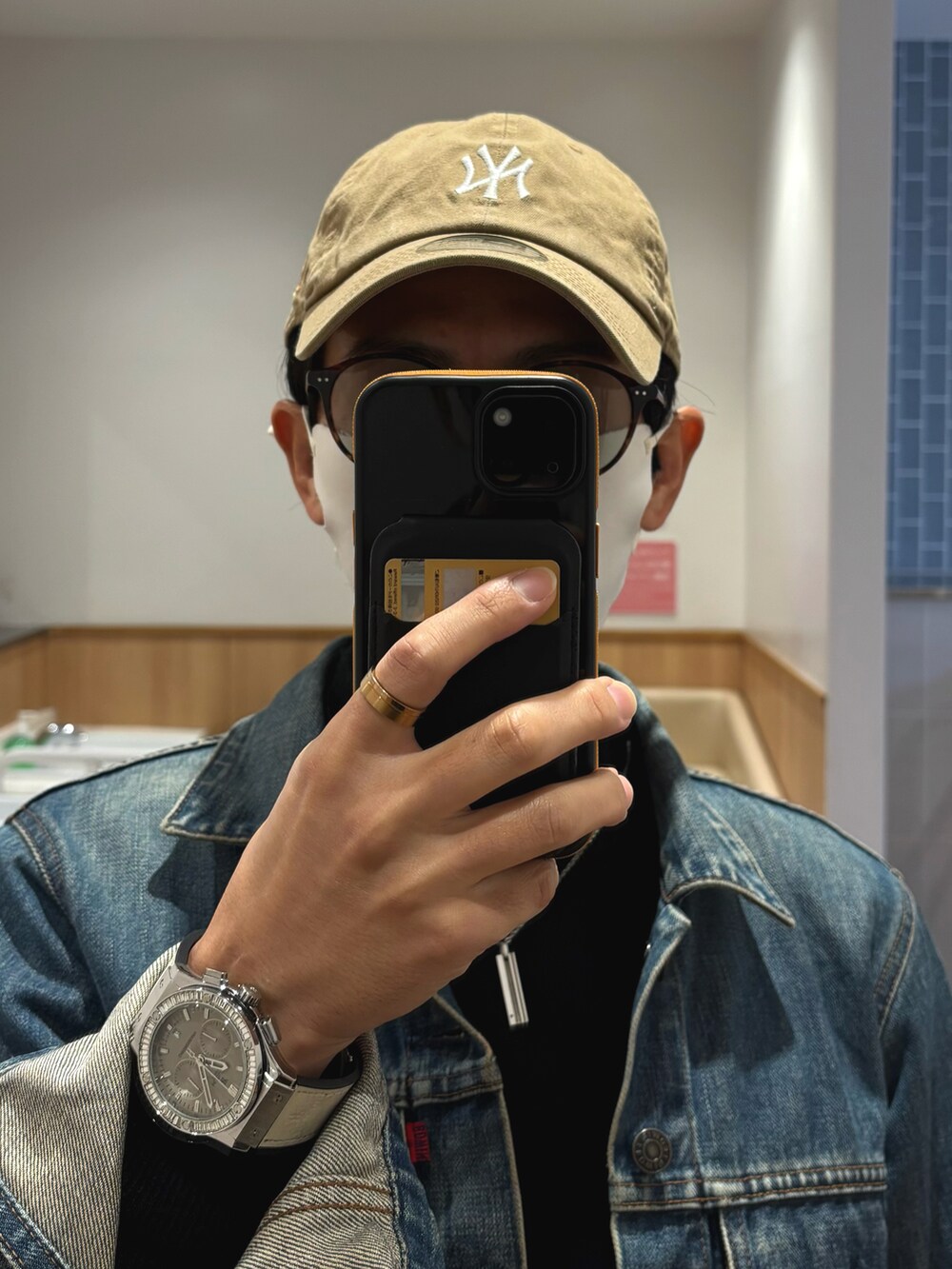 ホワイト系のスニーカー、ブラック系のニット/セーター、ブルー系のデニムジャケットを着用したメンズの秋コーディネートの4枚目の写真