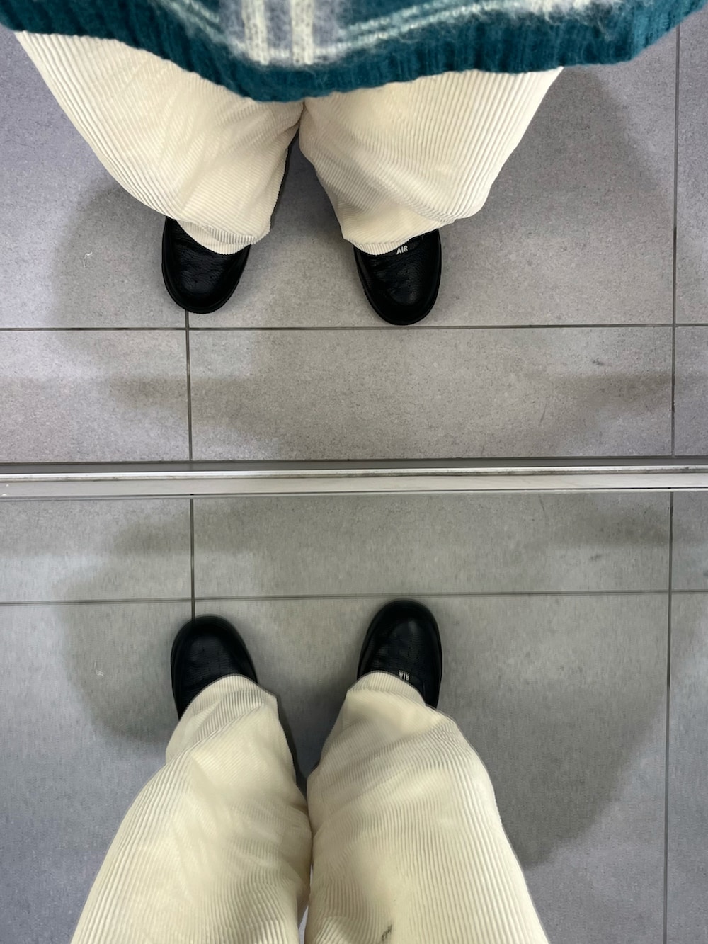 グリーン系のニット/セーター、ホワイト系のパンツ、ブラック系のスニーカーを着用したメンズの冬コーディネートの3枚目の写真