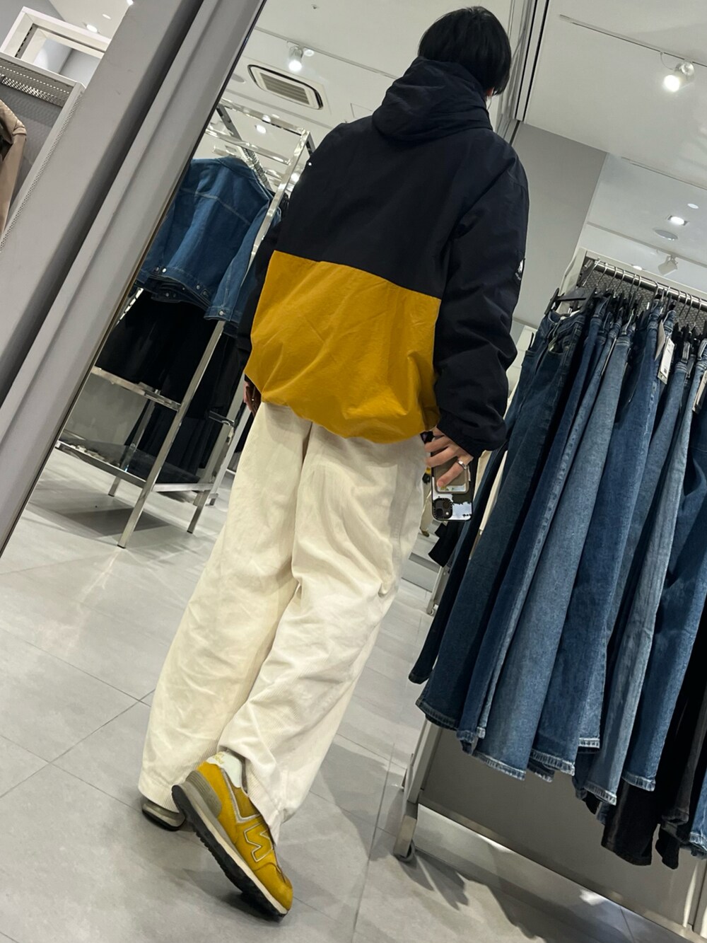 イエロー系のスニーカー、ホワイト系のパンツ、ブルー系のナイロンジャケットを着用したメンズの冬コーディネートの2枚目の写真