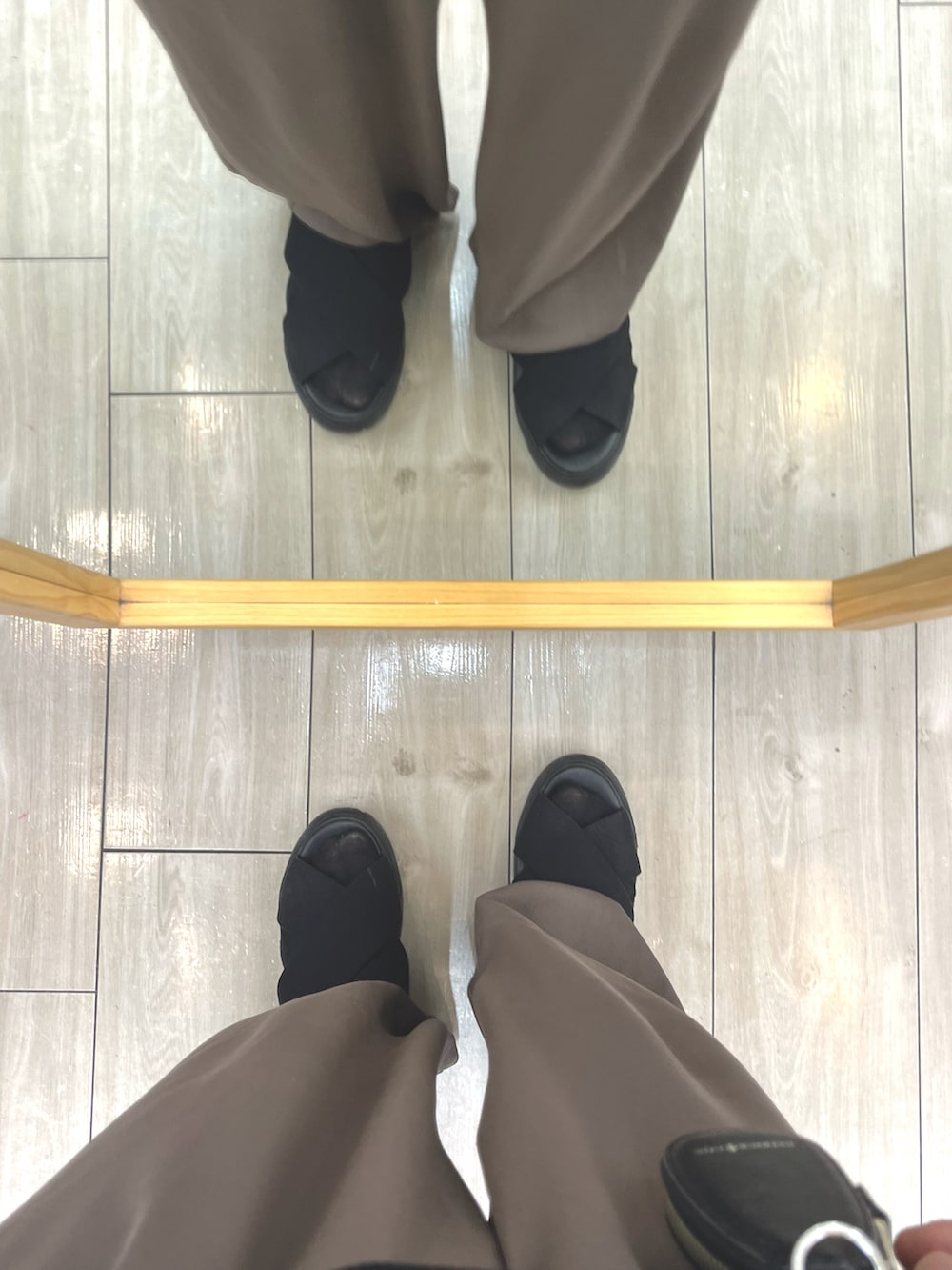 ブラウン系のパンツ、ブラック系のポロシャツ、ブラック系のサンダルを着用したメンズの秋コーディネートの5枚目の写真