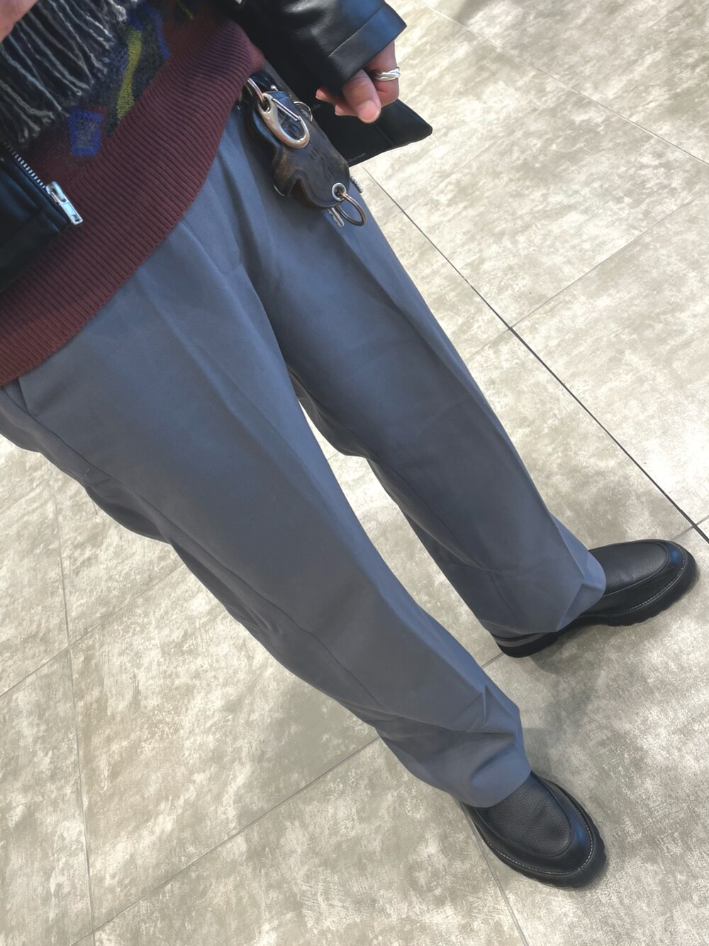 グレー系のパンツ、ブラック系のドレスシューズ、ブラック系のライダースジャケットを着用したメンズの春コーディネートの3枚目の写真