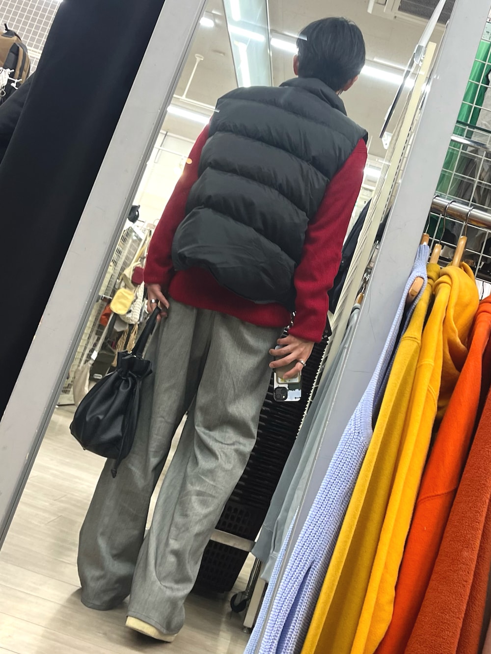 グレー系のスラックス、ブラック系のショルダーバッグ、ホワイト系のスニーカーを着用したメンズの冬コーディネートの2枚目の写真