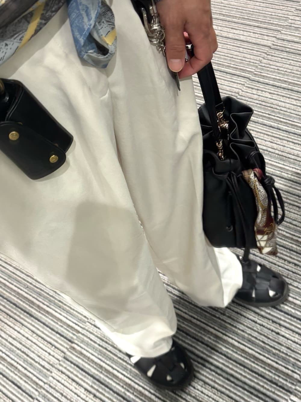ホワイト系のスラックス、ブラック系のTシャツ/カットソー、ブラック系のサンダルを着用したメンズの夏コーディネートの3枚目の写真