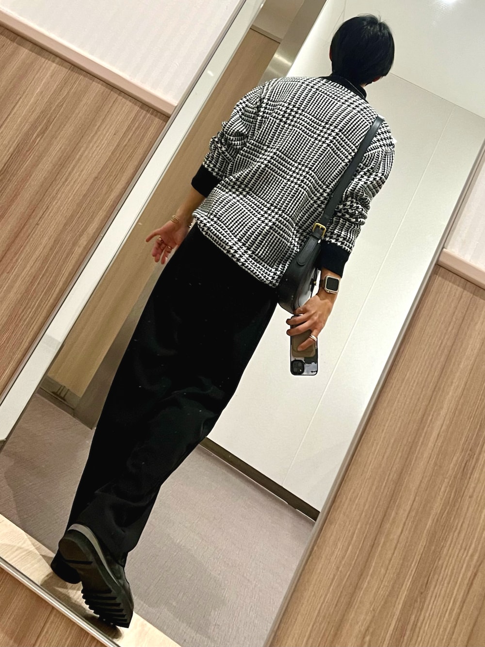 ブラック系のドレスシューズ、ブラック系のスラックス、ホワイト系のニット/セーターを着用したメンズの冬コーディネートの2枚目の写真