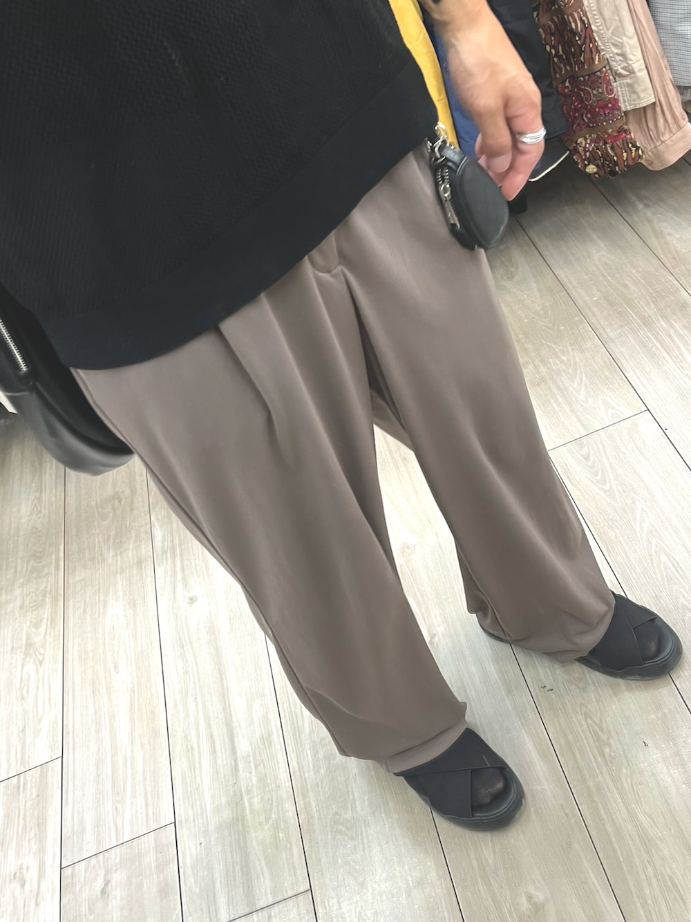 ブラウン系のパンツ、ブラック系のポロシャツ、ブラック系のサンダルを着用したメンズの秋コーディネートの3枚目の写真