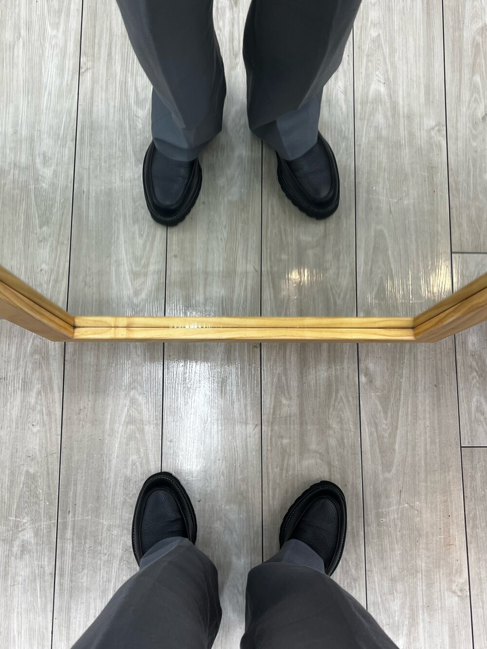 グレー系のパンツ、ブラック系のドレスシューズ、ブラック系のショルダーバッグを着用したメンズの冬コーディネートの5枚目の写真