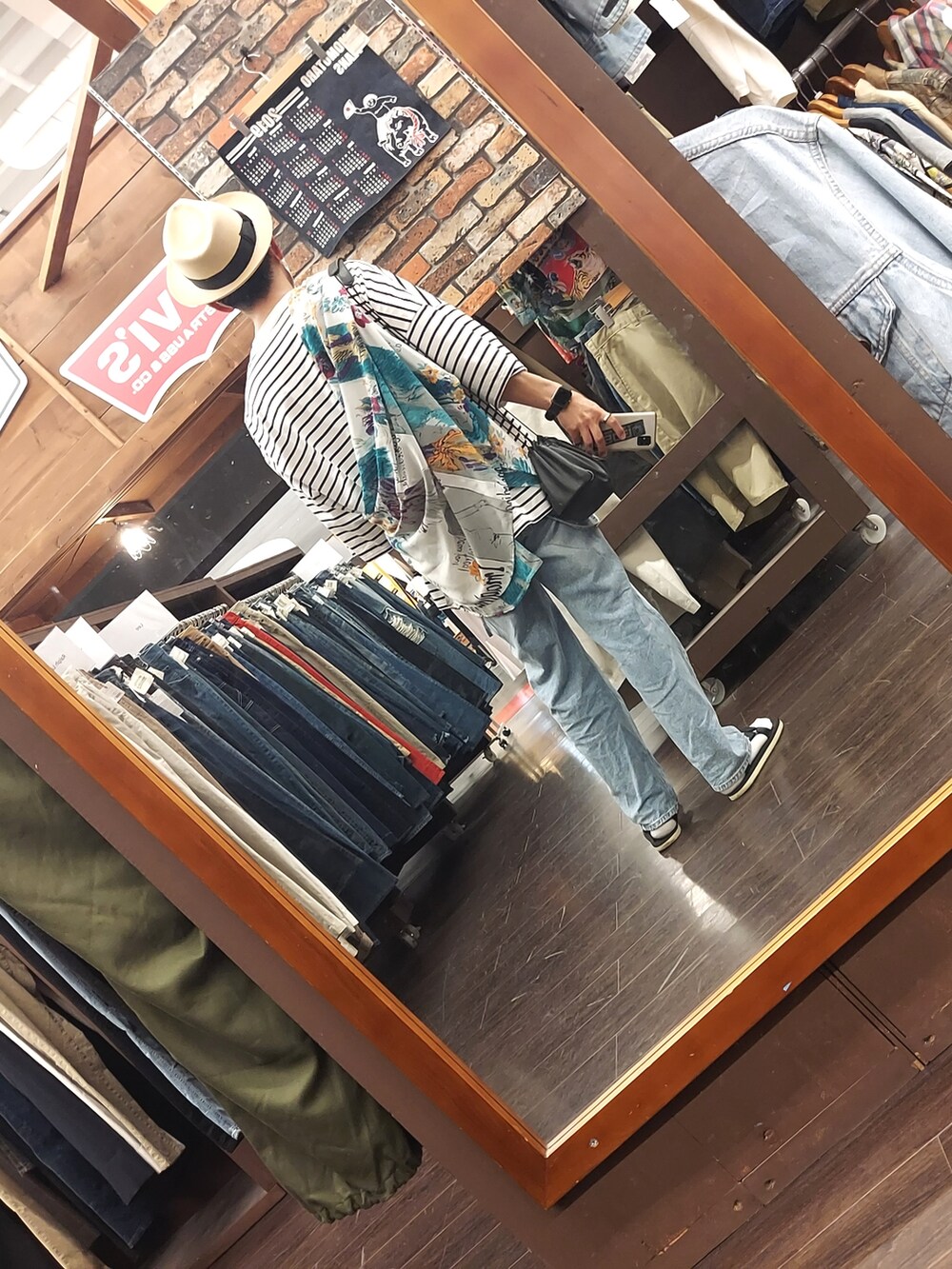 ブルー系のデニムパンツ、ホワイト系のTシャツ/カットソー、ブラック系のサンダルを着用したメンズの夏コーディネートの2枚目の写真