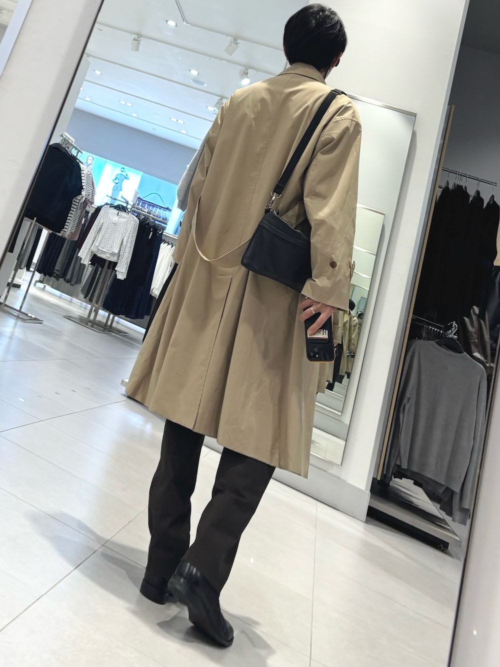 ブルー系のカーディガン/ボレロ、ブラウン系のスラックス、ベージュ系のトレンチコートを着用したメンズの冬コーディネートの2枚目の写真