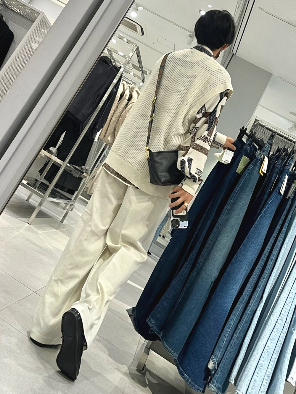 ブラック系のローファー、ホワイト系のスラックス、ベージュ系のベストを着用したメンズの秋コーディネートの2枚目の写真