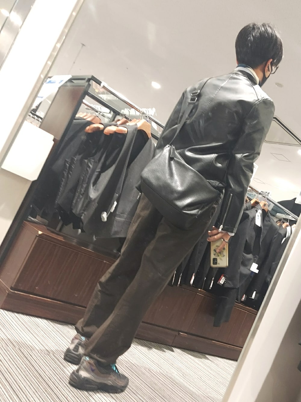 ブラウン系のパンツ、ブラック系のスニーカー、ブラック系のライダースジャケットを着用したメンズの春コーディネートの2枚目の写真