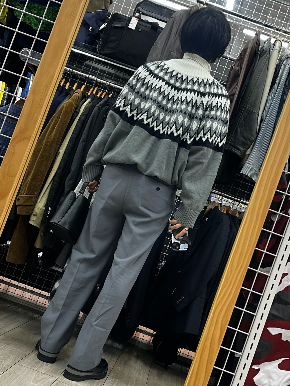 グレー系のパンツ、ブラック系のドレスシューズ、ブラック系のショルダーバッグを着用したメンズの冬コーディネートの2枚目の写真