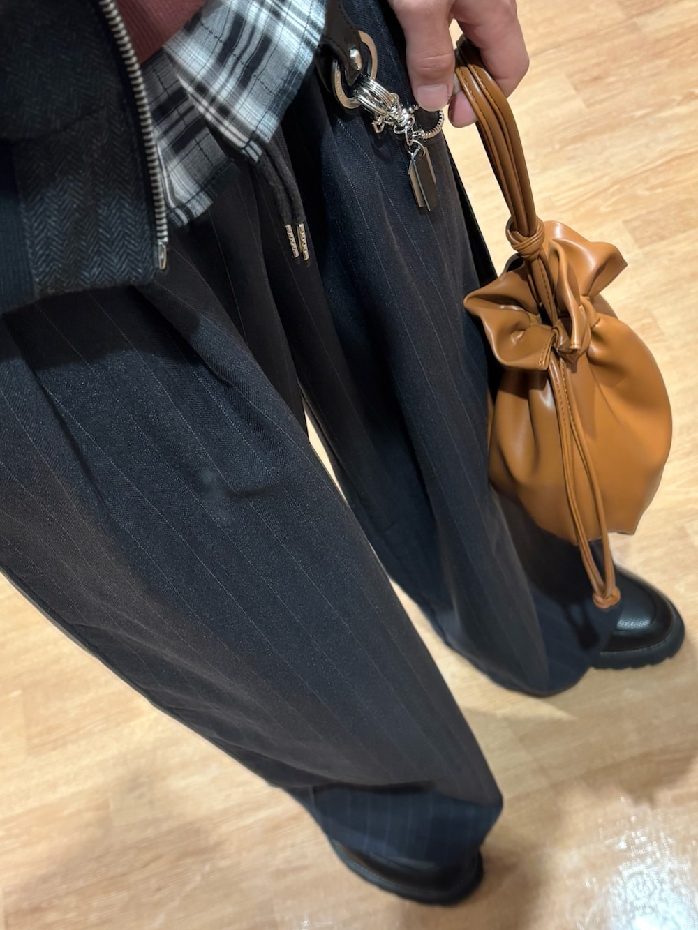 ブラウン系のスウェット、ブラウン系のショルダーバッグ、ブラック系のドレスシューズを着用したメンズの冬コーディネートの3枚目の写真