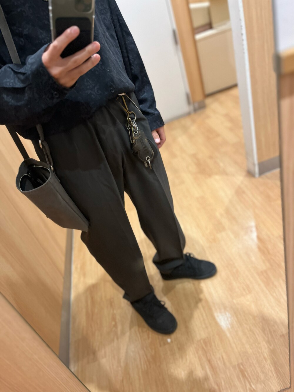 ブラウン系のパンツ、ブラック系のスニーカー、グレー系のショルダーバッグを着用したメンズの秋コーディネートの3枚目の写真