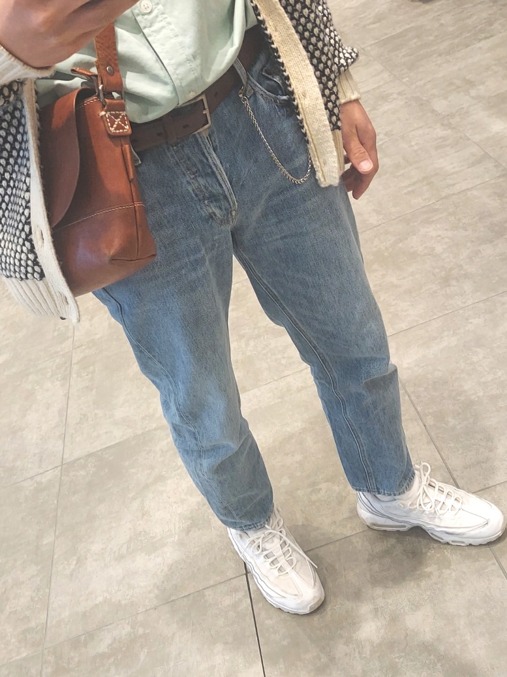 ブルー系のデニムパンツ、ホワイト系のスニーカー、ブラウン系のボディバッグ/ウエストポーチを着用したメンズの春コーディネートの3枚目の写真