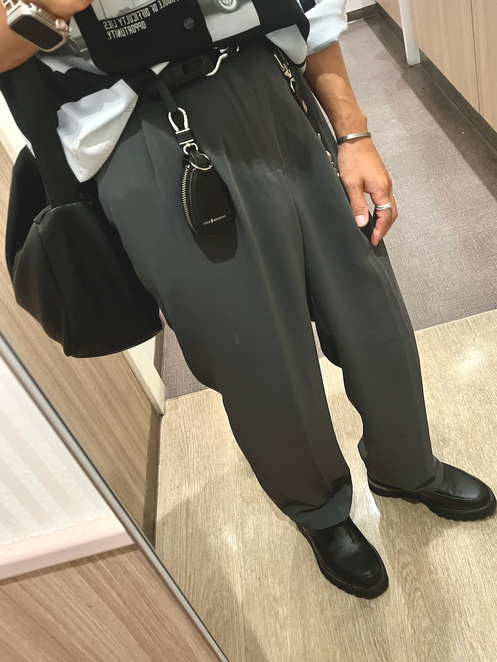 グレー系のスラックス、ブラック系のドレスシューズ、ブラック系のショルダーバッグを着用したメンズの秋コーディネートの3枚目の写真