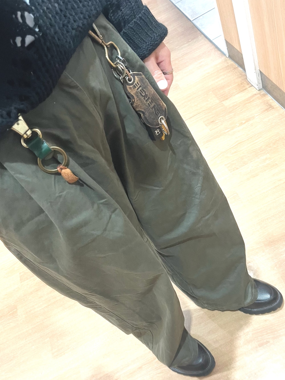 グリーン系のパンツ、ブラック系のドレスシューズ、ブラック系のニット/セーターを着用したメンズの春コーディネートの3枚目の写真