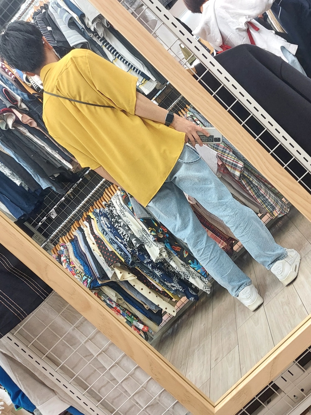 ブルー系のデニムパンツ、ホワイト系のスニーカー、ブラック系のショルダーバッグを着用したメンズの春コーディネートの4枚目の写真