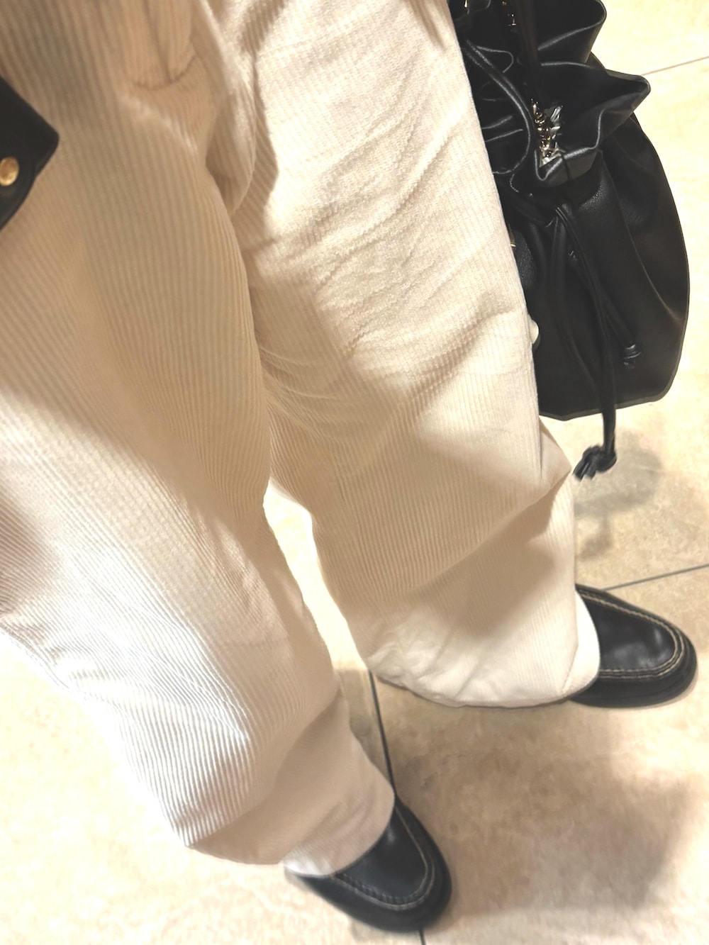 ブラック系のブルゾン、ホワイト系のパンツ、ブラック系のローファーを着用したメンズの春コーディネートの3枚目の写真