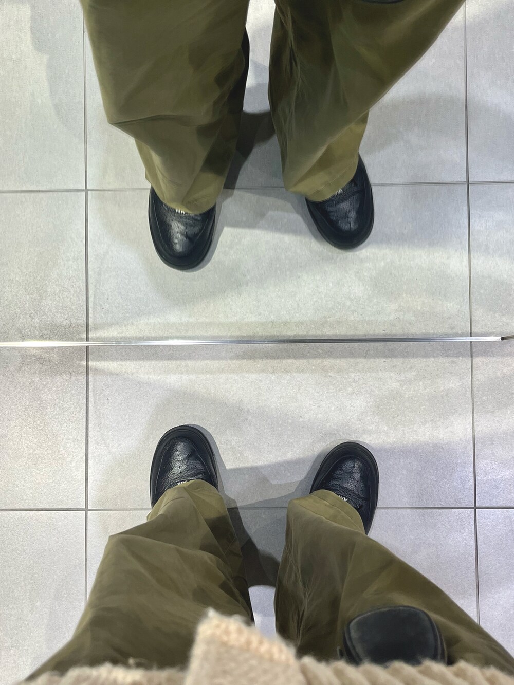 グリーン系のパンツ、ブラック系のスニーカー、ベージュ系のカーディガン/ボレロを着用したメンズの冬コーディネートの5枚目の写真