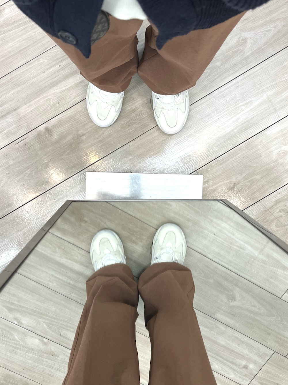 ブラウン系のパンツ、ホワイト系のスニーカー、ブラック系のショルダーバッグを着用したメンズの秋コーディネートの4枚目の写真