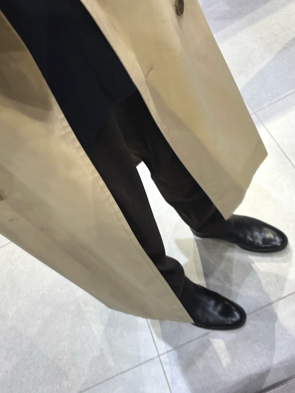 ブルー系のカーディガン/ボレロ、ブラウン系のスラックス、ベージュ系のトレンチコートを着用したメンズの冬コーディネートの3枚目の写真