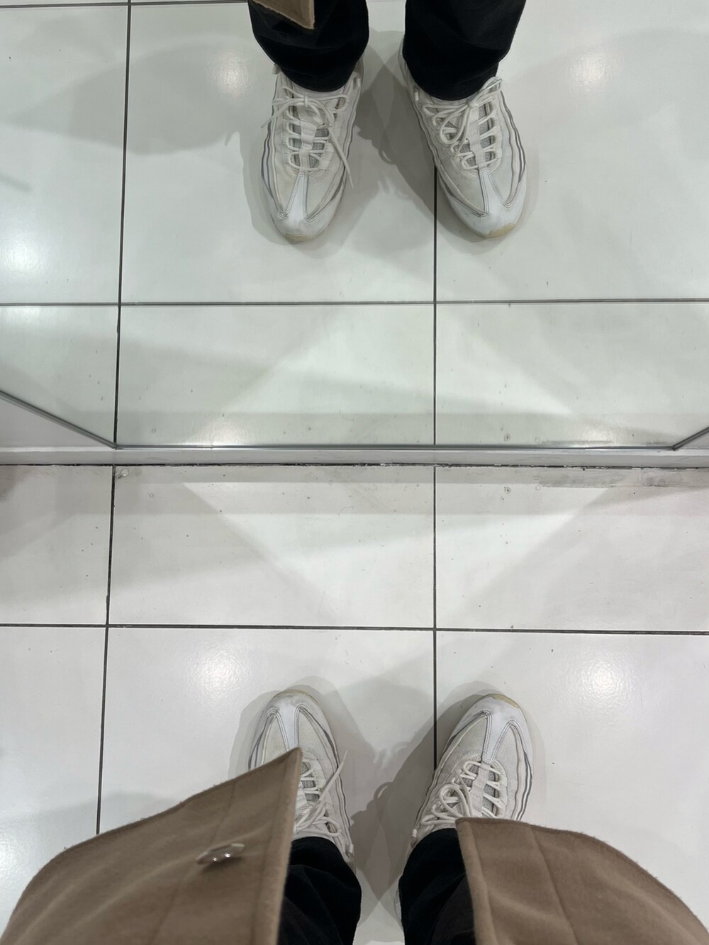 ブラック系のパンツ、ホワイト系のスニーカー、ベージュ系のムートンコートを着用したメンズの冬コーディネートの5枚目の写真