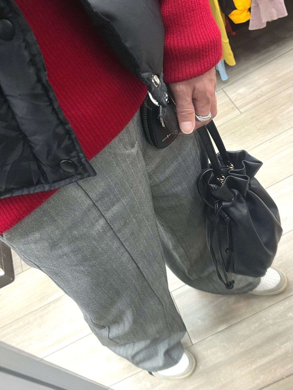 グレー系のスラックス、ブラック系のショルダーバッグ、ホワイト系のスニーカーを着用したメンズの冬コーディネートの3枚目の写真