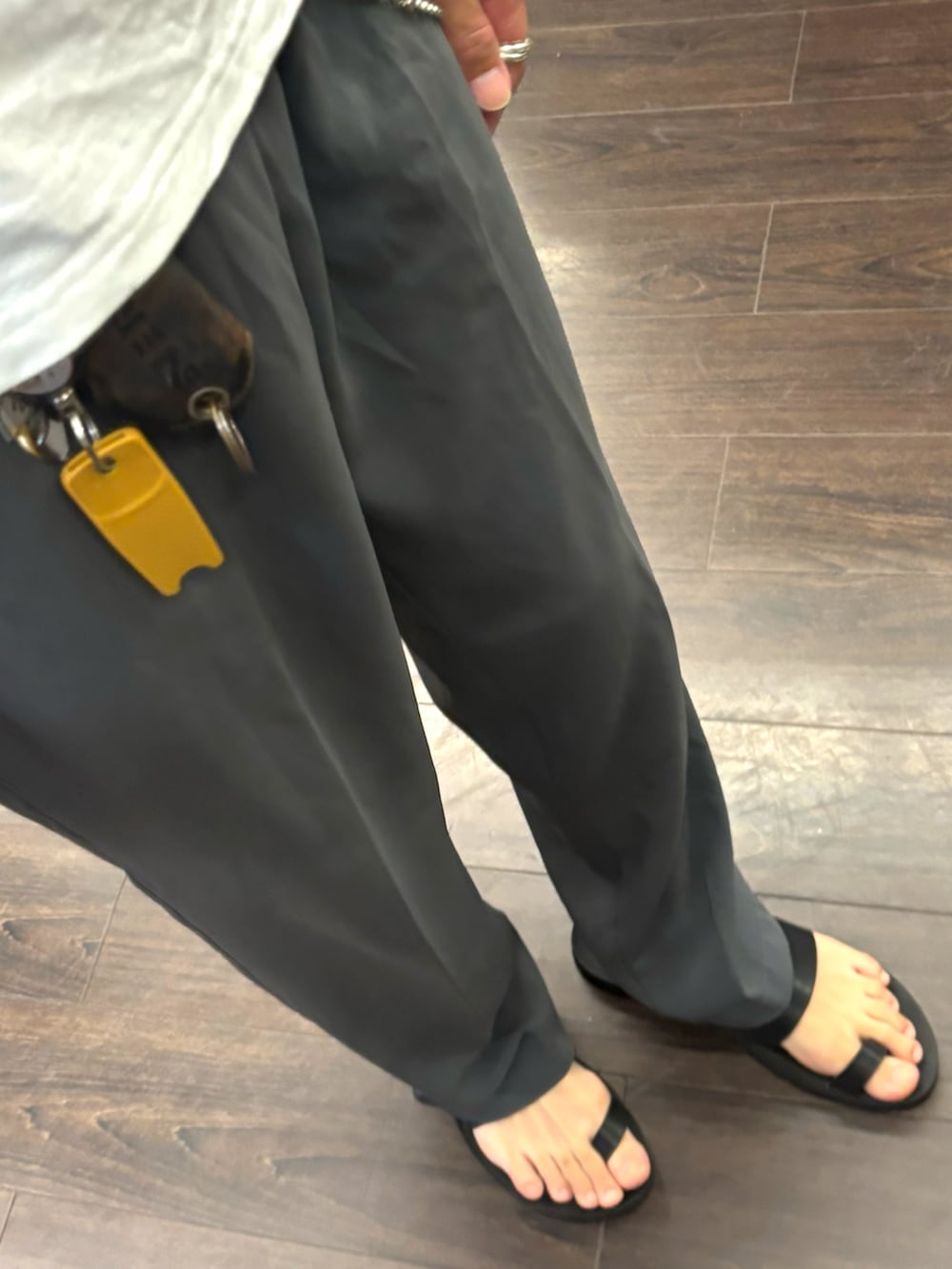 グレー系のスラックス、ブラック系のサンダル、ホワイト系のTシャツ/カットソーを着用したメンズの夏コーディネートの3枚目の写真