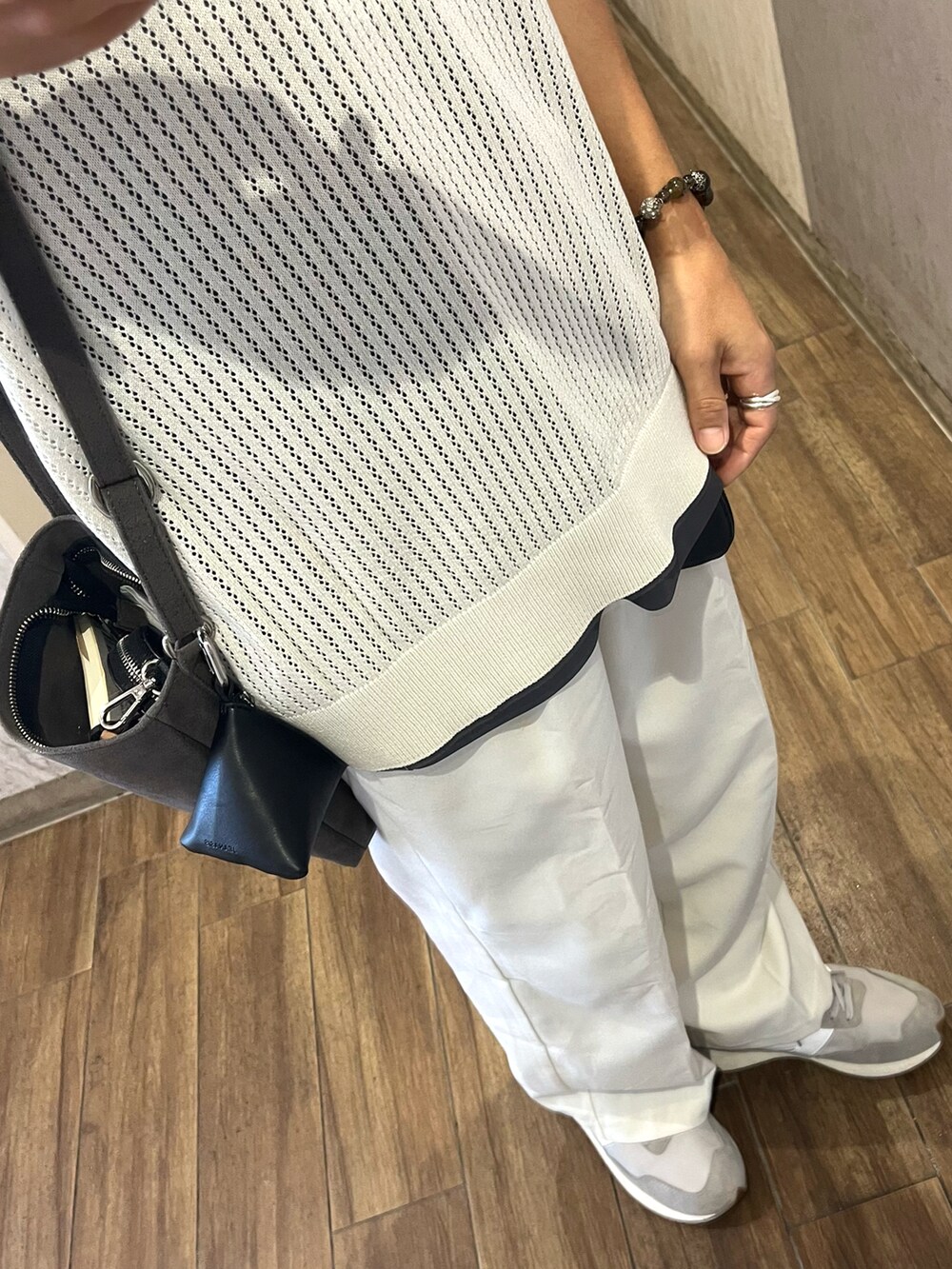 グレー系のスニーカー、ベージュ系のベスト、グレー系のショルダーバッグを着用したメンズの秋コーディネートの3枚目の写真