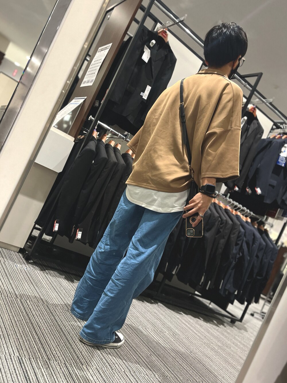 ブラック系のスニーカー、ブラック系のバッグ、ブルー系のデニムパンツを着用したメンズの秋コーディネートの2枚目の写真