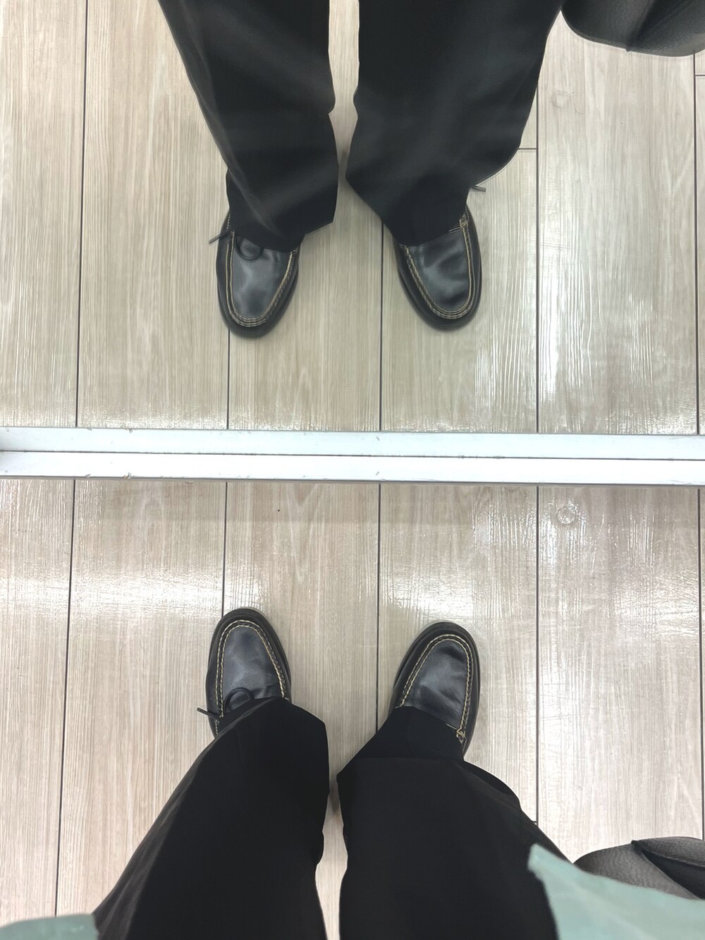 ブラック系のスラックス、ブラック系のローファー、ブラック系のショルダーバッグを着用したメンズの夏コーディネートの5枚目の写真