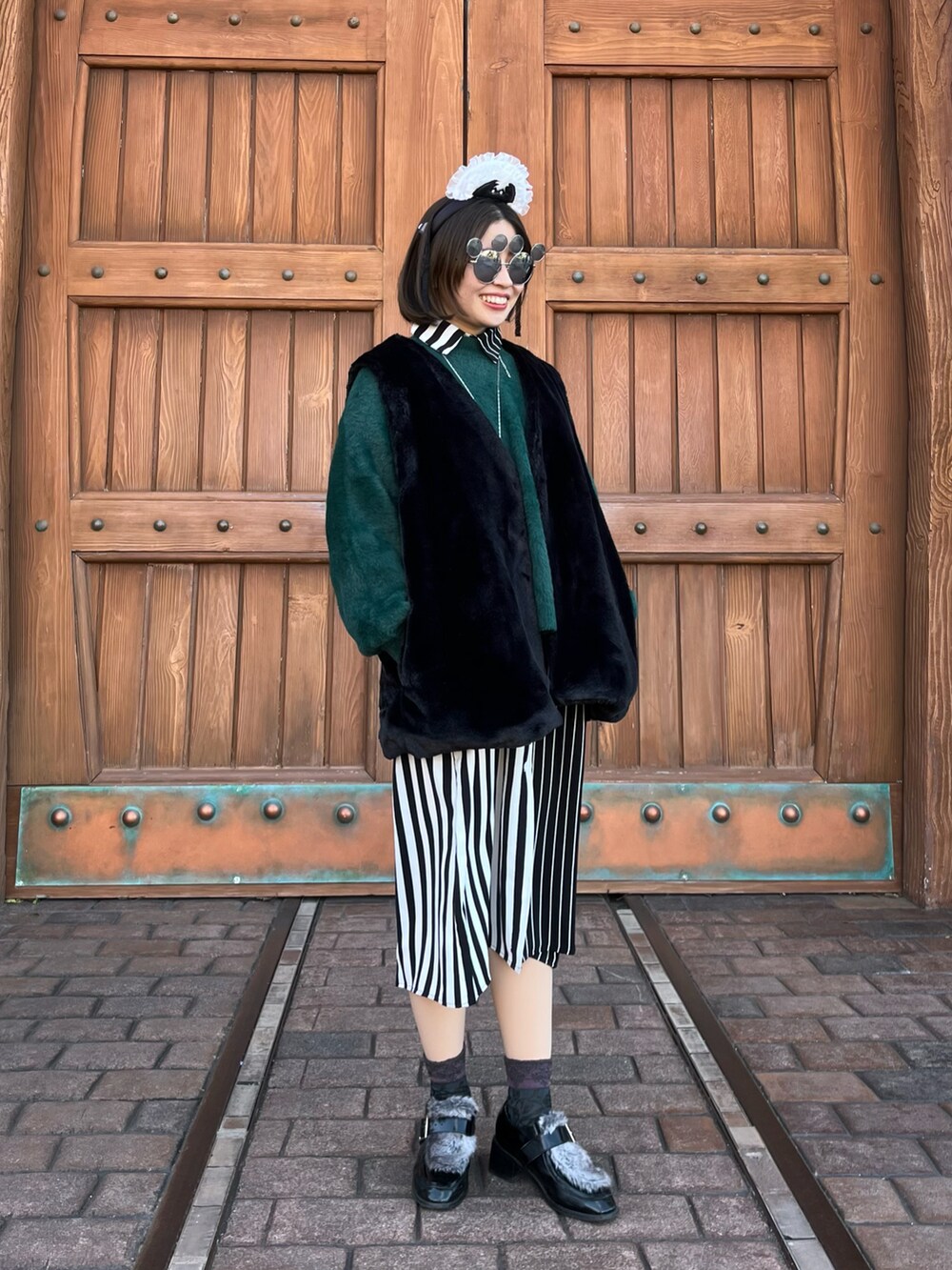 ブラック系のその他アウター、グリーン系のニット/セーター、ブラック系のワンピースを着用したレディースの冬コーディネートの2枚目の写真