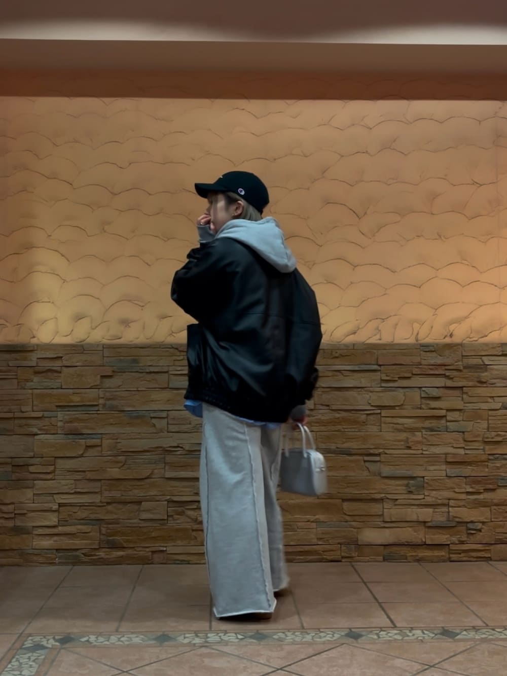 ブラック系のブルゾン、シルバー系のハンドバッグ、グレー系のスウェットパンツを着用したレディースの冬コーディネートの4枚目の写真