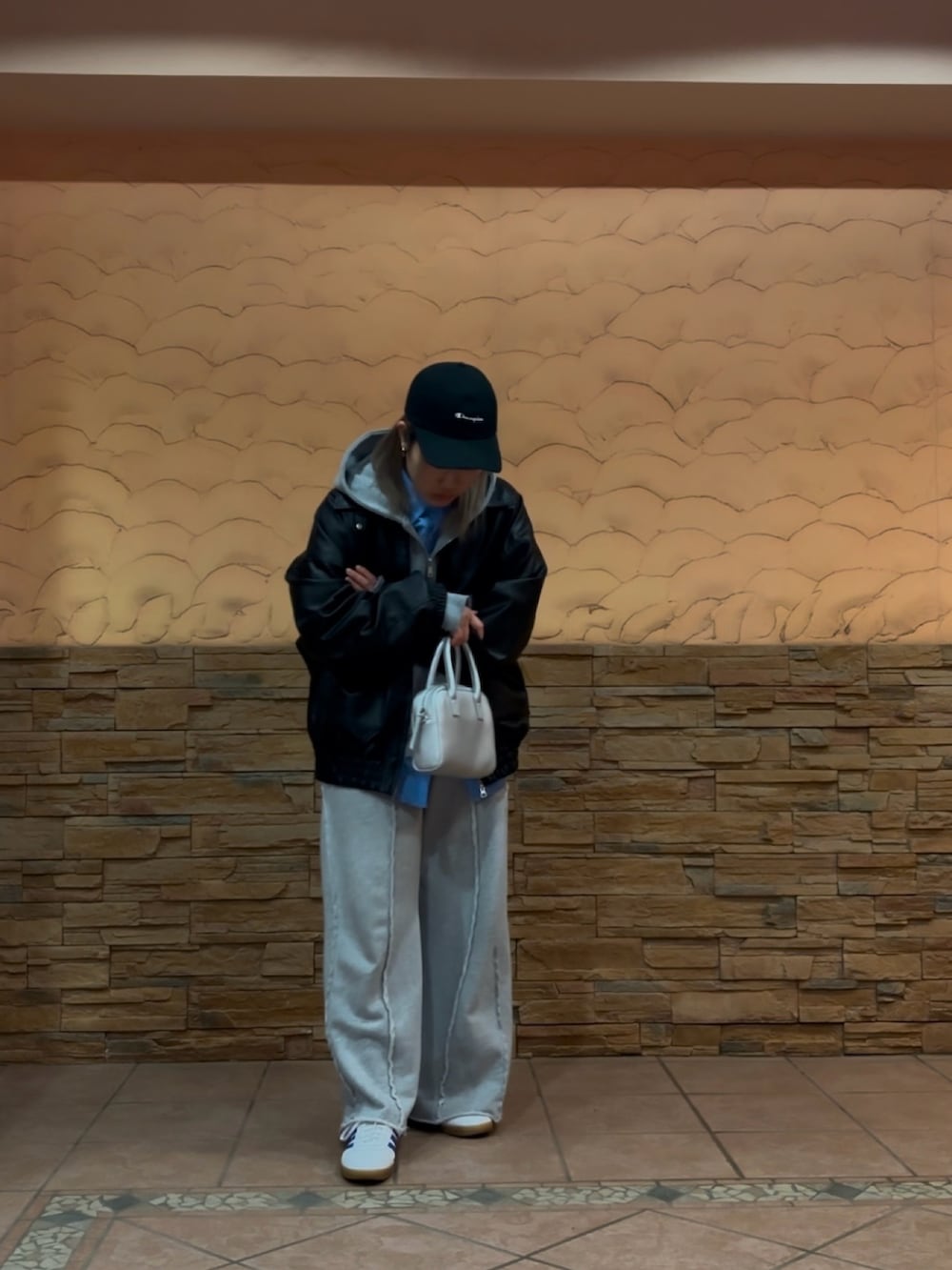 ブラック系のブルゾン、シルバー系のハンドバッグ、グレー系のスウェットパンツを着用したレディースの冬コーディネートの3枚目の写真