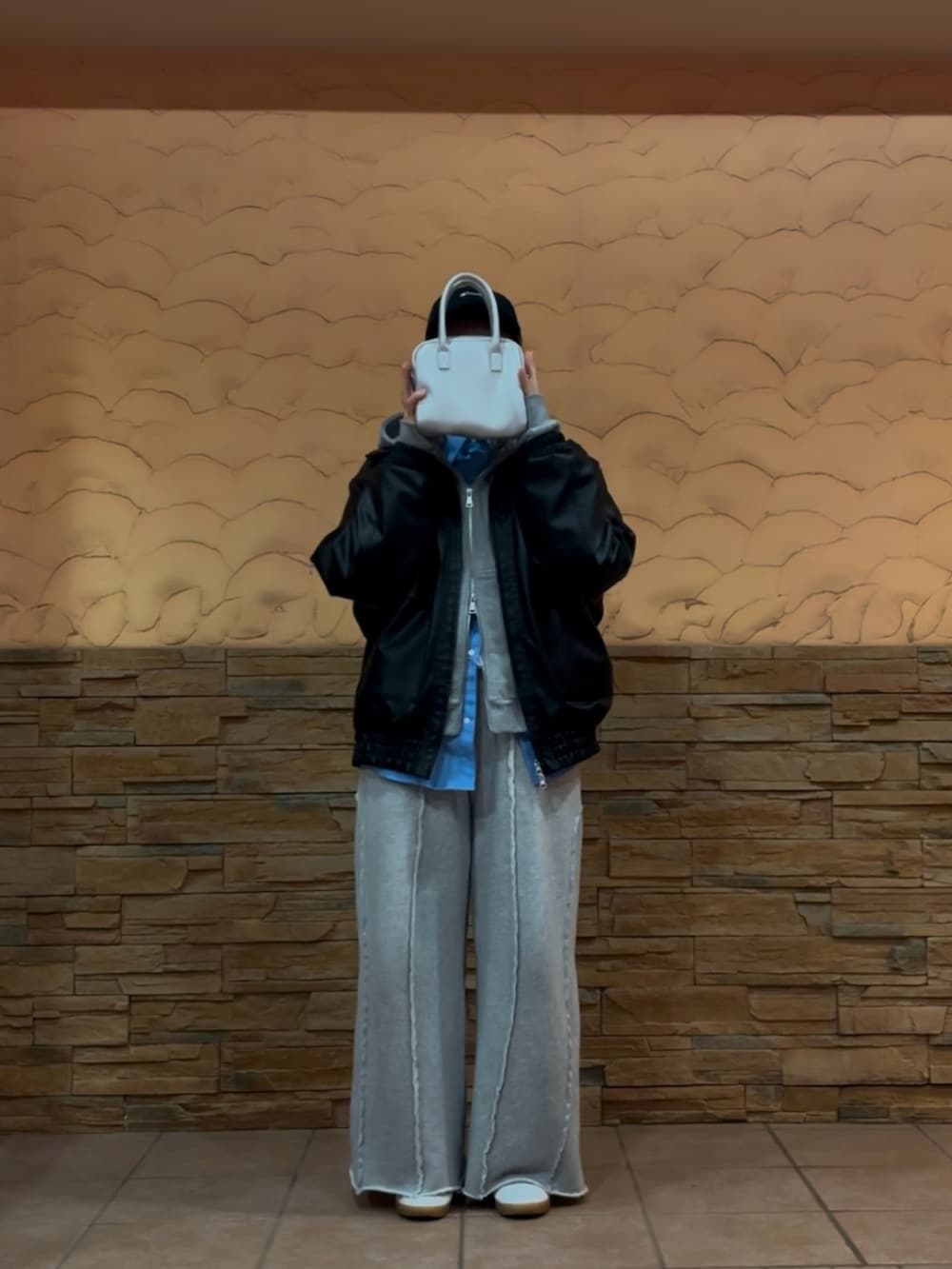 ブラック系のブルゾン、シルバー系のハンドバッグ、グレー系のスウェットパンツを着用したレディースの冬コーディネートの2枚目の写真