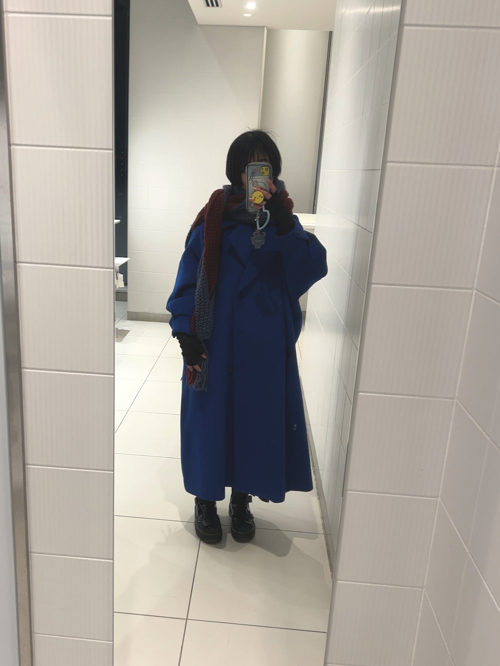 ブラック系のブーツ、ブルー系のチェスターコート、レッド系のスウェットを着用したレディースの冬コーディネートの2枚目の写真